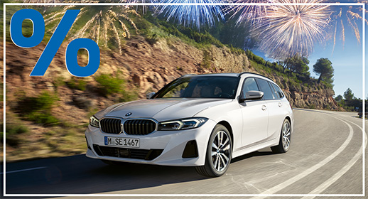 Ein weißer BMW 3er Touring fährt dynamisch eine kurvenreiche Straße entlang, die von bewaldeten Hügeln gesäumt ist. Das Bild ist als Werbegrafik gestaltet: In der oberen linken Ecke prangt ein großes, blaues Prozentzeichen (%), während in der oberen rechten Ecke ein Feuerwerk vor blauem Himmel zu sehen ist. Ein schmaler weißer Rahmen fasst das gesamte Motiv ein und signalisiert besondere Rabattaktionen im Rahmen der Jahresstart-Kampagne.