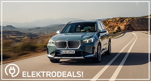 "Vorderansicht eines grauen BMW iX1 Elektro-SUVs mit Kennzeichen 'MDI 276E', der auf einer kurvigen Landstraße fährt. Mit 'Elektrodeals!'-Logo."