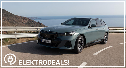 Dreiviertel-Vorderansicht einer hellgrauen BMW i5 Elektro-Limousine mit Kennzeichen 'MDY 237E', parkend auf Asphalt vor einer Betonmauer. Mit 'Elektrodeals!'-Logo."