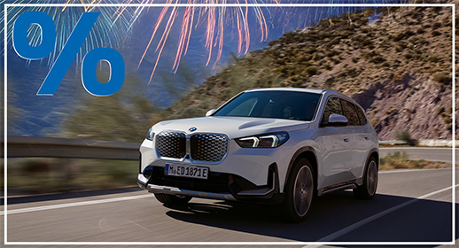 In einer lichtdurchfluteten urbanen Szene parkt ein leuchtend gelber MINI Cooper mit weißem Dach vor einer historischen Backsteinfassade mit kunstvollen Rundbogenfenstern. Eine Frau mit langen blonden Haaren, bekleidet mit einem dunklen Blazer und hellen Jeans, steht an der Fahrerseite und öffnet gerade die Tür. Das Bild vermittelt ein Gefühl von Freiheit und Unbeschwertheit, das durch den Service MINI Proactive Care unterstützt wird. Dieser vorausschauende Dienst überwacht den Fahrzeugzustand kontinuierlich, um technische Probleme oder Wartungsbedarf zu erkennen, bevor sie den Fahrer einschränken.