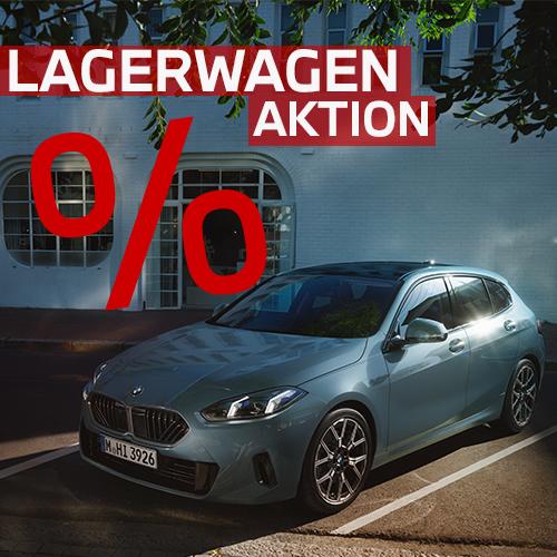 Ein BMW 1er in modernem Grau-Blau parkt stilvoll vor einem weißen Gebäude mit großen Rundbogenfenstern. Das Spiel aus Licht und Schatten auf dem Lack verleiht der Szene eine urbane, exklusive Note. Die knallrote Grafik der Lagerwagen-Aktion bricht die ruhige Optik auf und weist effektiv auf die Sonderkonditionen im ersten Quartal 2026 hin.