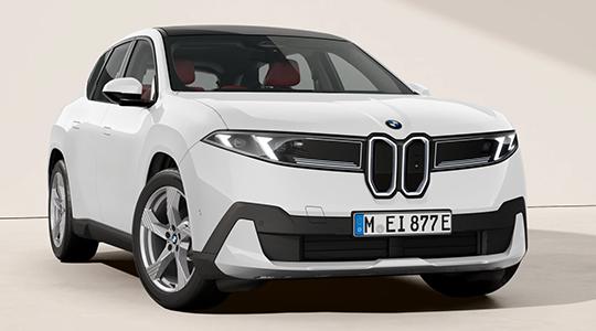Auf dem Bild ist ein weißer BMW iX3 zu sehen, der frontal fotografiert wurde. Das Auto ist in einem Studio vor einem hellen Hintergrund platziert. Das Dach ist in kontrastierendem Schwarz gehalten. Die Frontpartie ist markant gestaltet, mit einer großen, rechteckigen "Doppel-Niere", die typisch für BMW ist, aber bei diesem Elektro-SUV geschlossen und schwarz ist. Die schlanken, horizontalen Scheinwerfer unterstreichen das moderne Design. Am unteren Teil der Frontstoßstange befinden sich schwarze Kunststoffelemente. Man kann auch durch die Scheiben die roten Sitze im Innenraum erkennen.