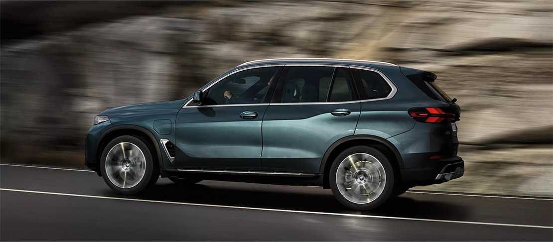 Dunkelblauer BMW X5 SUV fährt auf einer Straße mit Felswand im Hintergrund